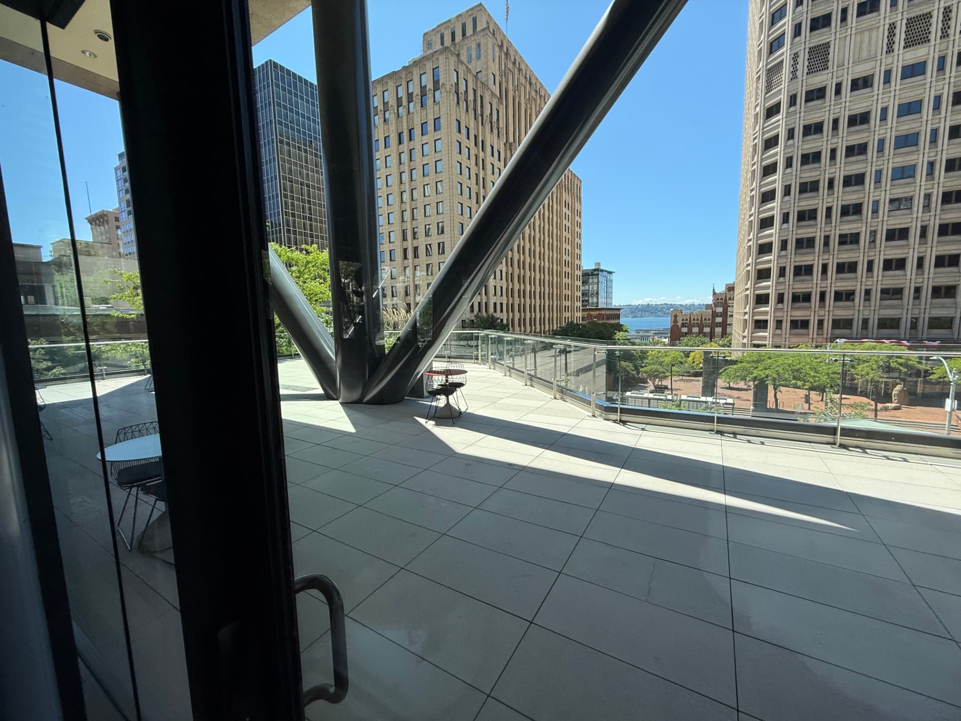 Outdoor terrace on the 7th floor with tile flooring, café tables, and views toward Elliott Bay.