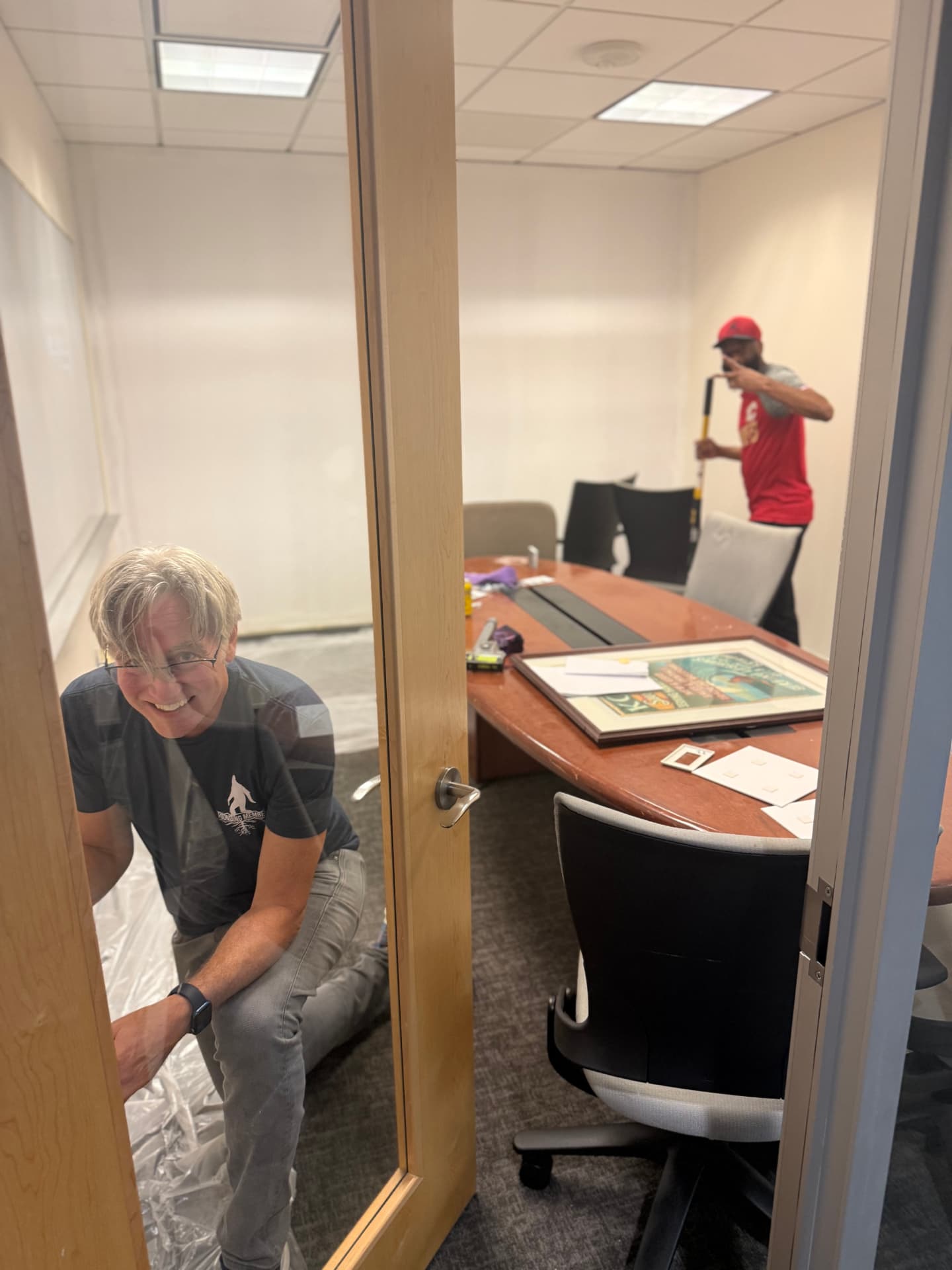 Friends assembling furniture in a glass-walled meeting room