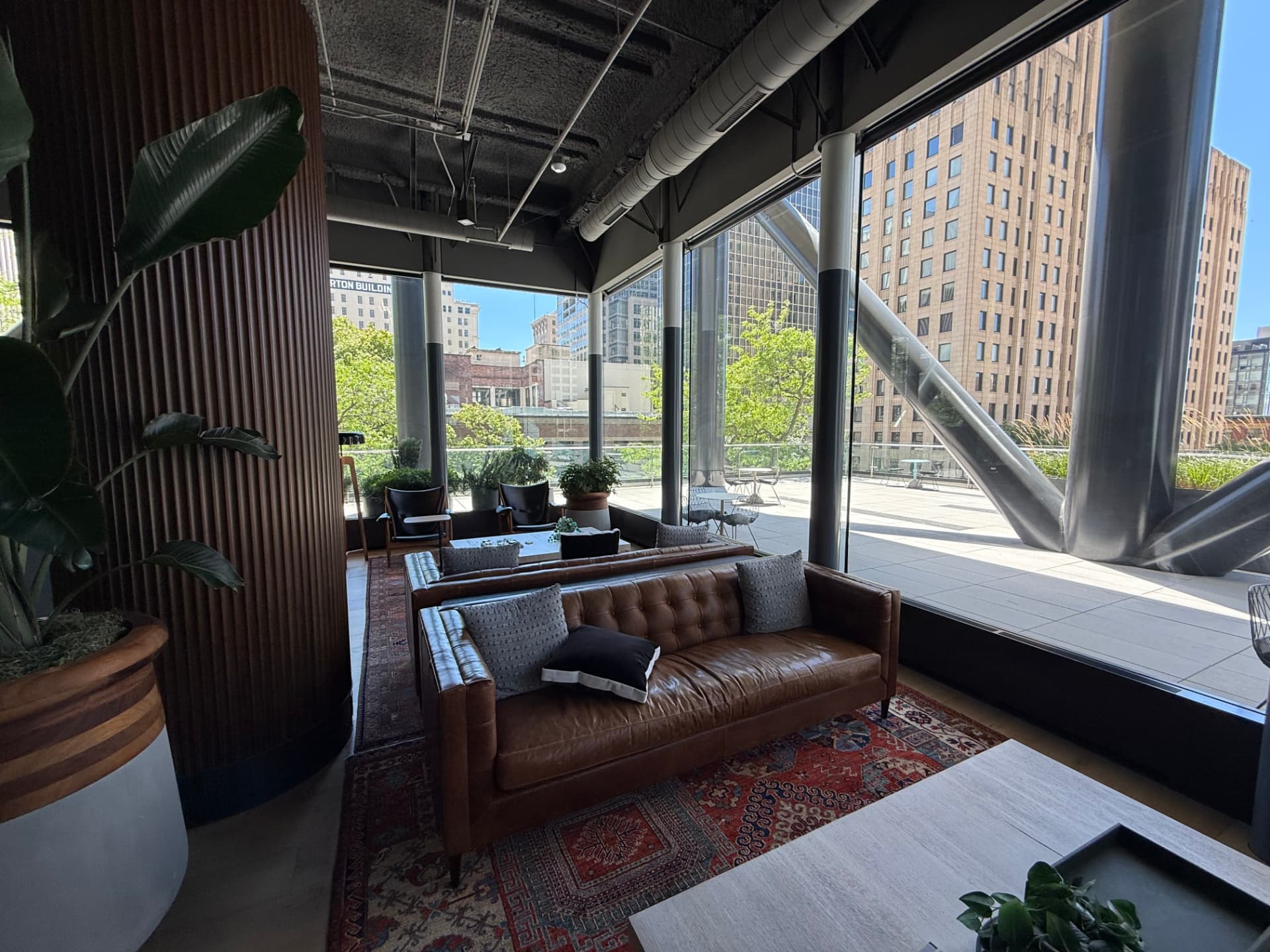 Leather sofa in front of floor-to-ceiling glass opening onto the outdoor terrace.