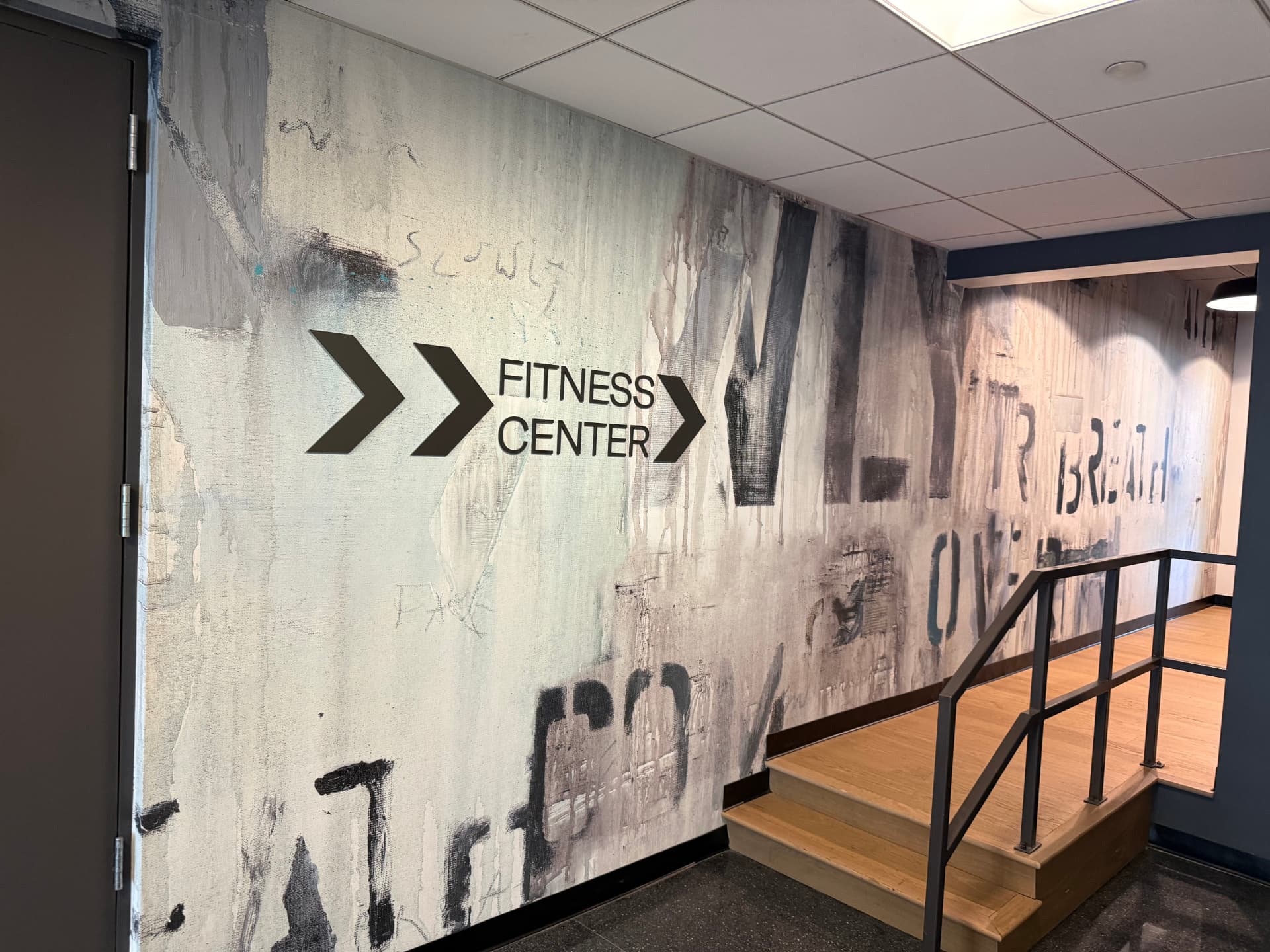Hand-painted mural on a wall with the words Fitness Center and arrows.