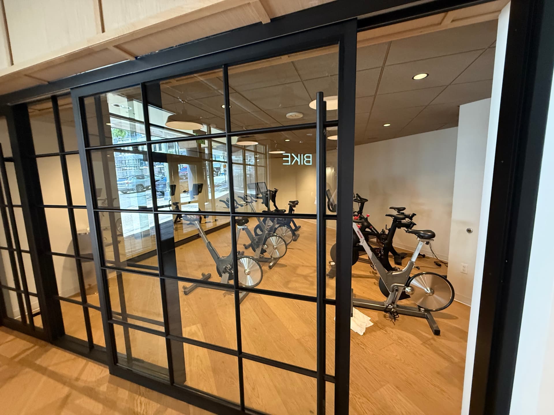 Spin studio with stationary bikes behind a black-framed glass wall.