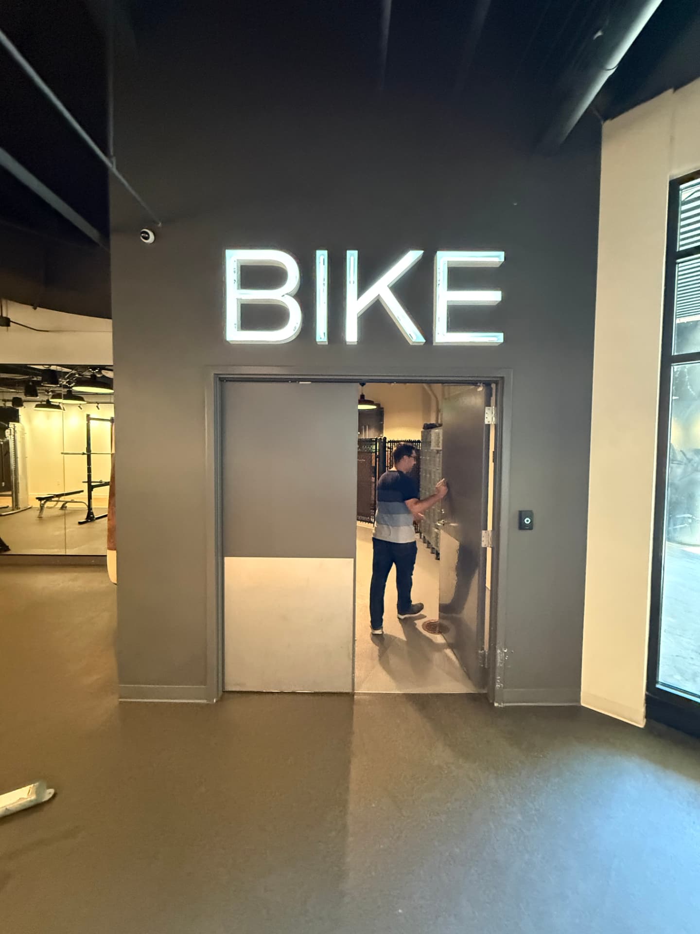 Indoor bike storage entrance with a large illuminated BIKE sign above the door.