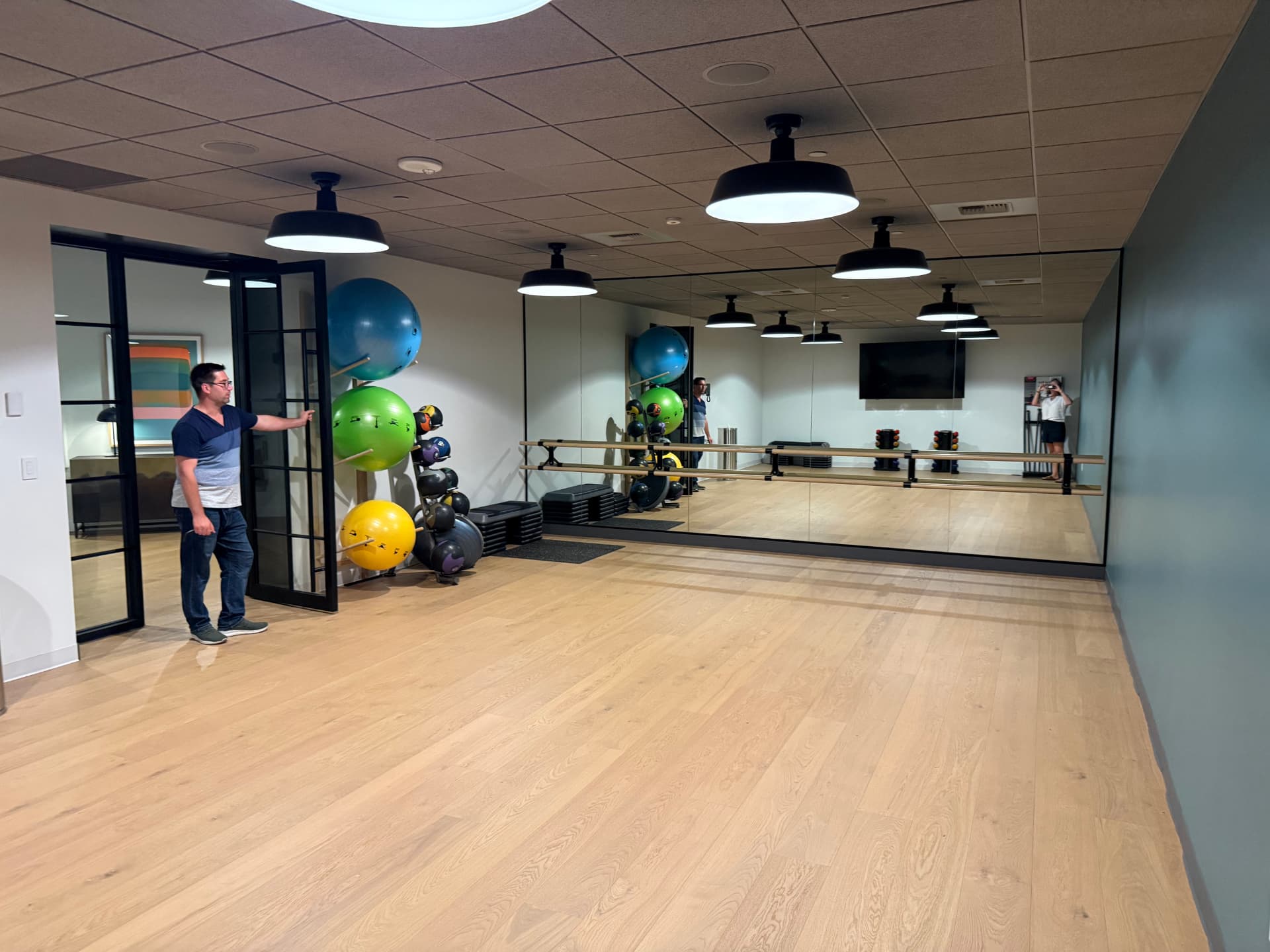Bright yoga and barre studio with a barre and exercise balls.