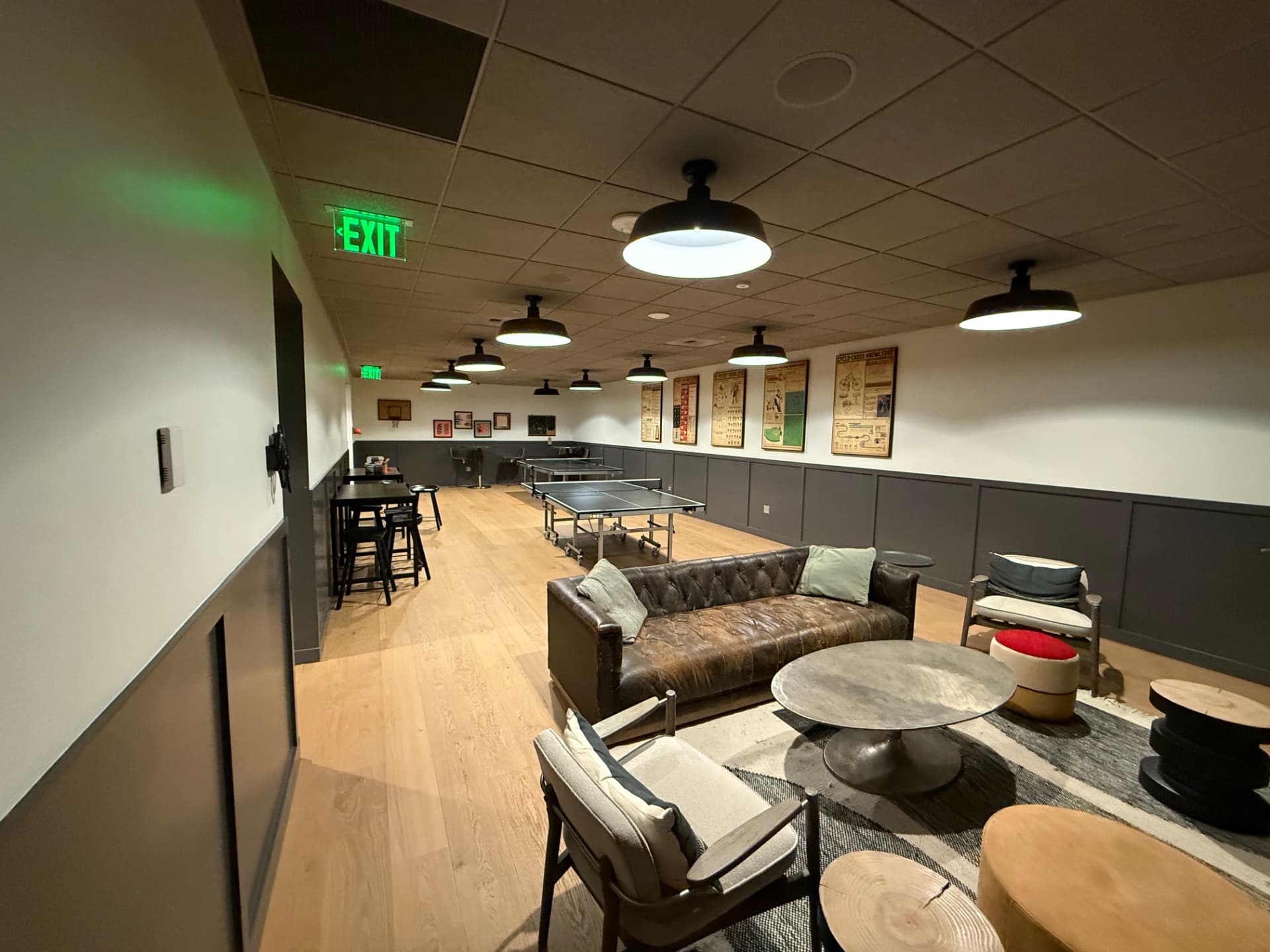 Tenant game lounge with a leather sofa, coffee table, and ping-pong tables in the background.