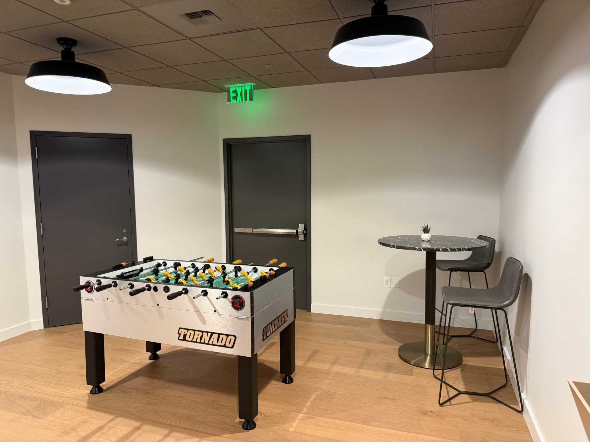 White foosball table next to a small high-top table in a modern lounge area.