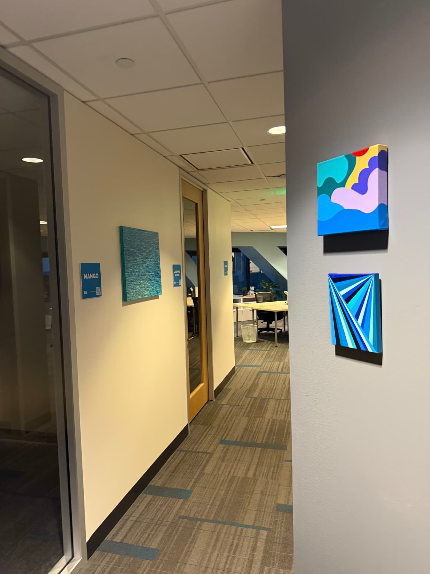 Hallway with artwork on the walls leading into The SWELL coworking area.